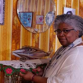 A person in a brightly decorated room next to a glass fish ornament