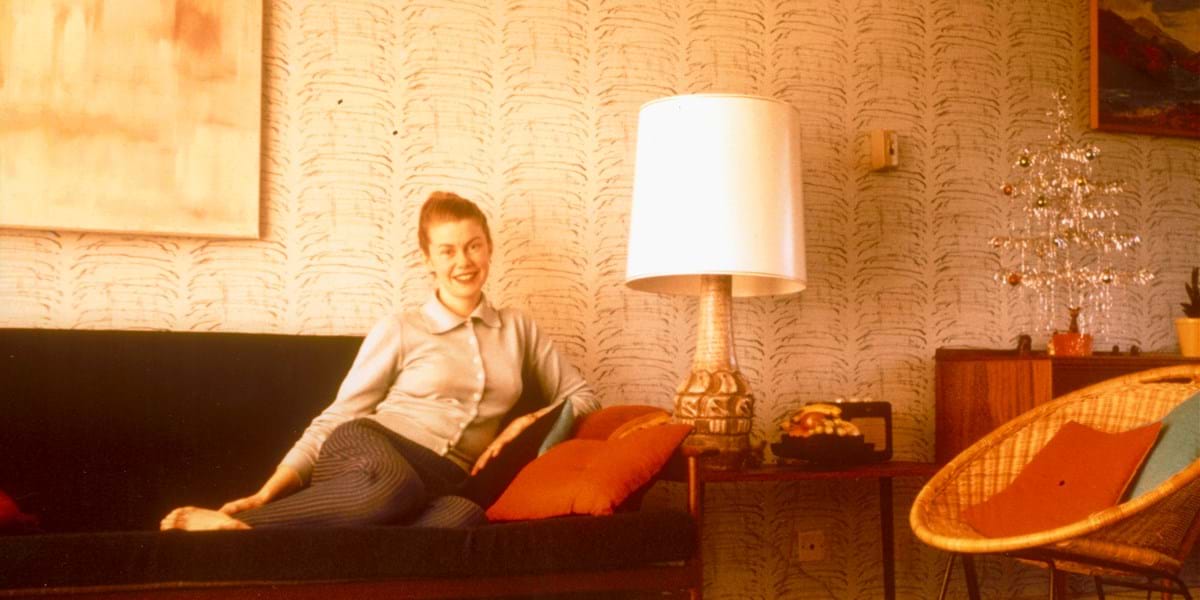 Person sitting on a sofa next to a large lamp