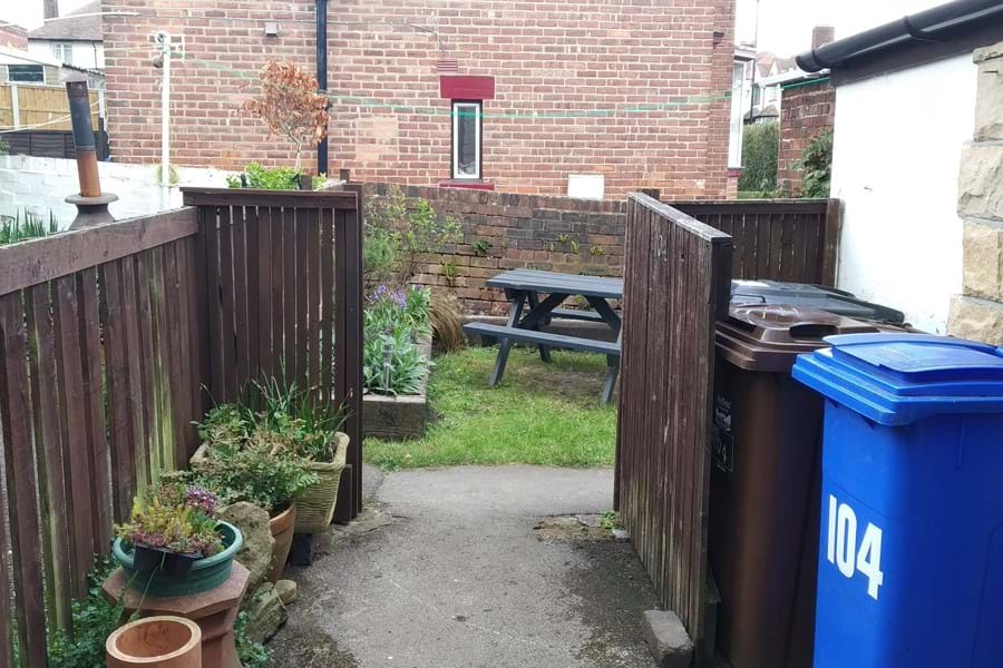 View through an open gate of a picnic bench on a patch of grass