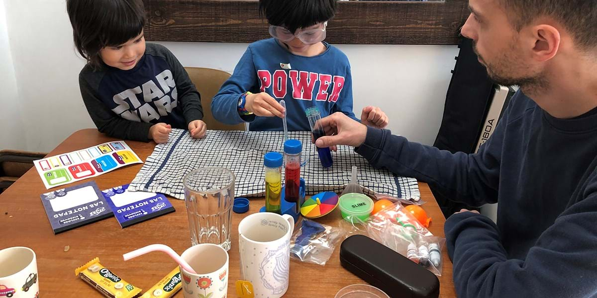 Children sat at a table with an adult leading a science lesson