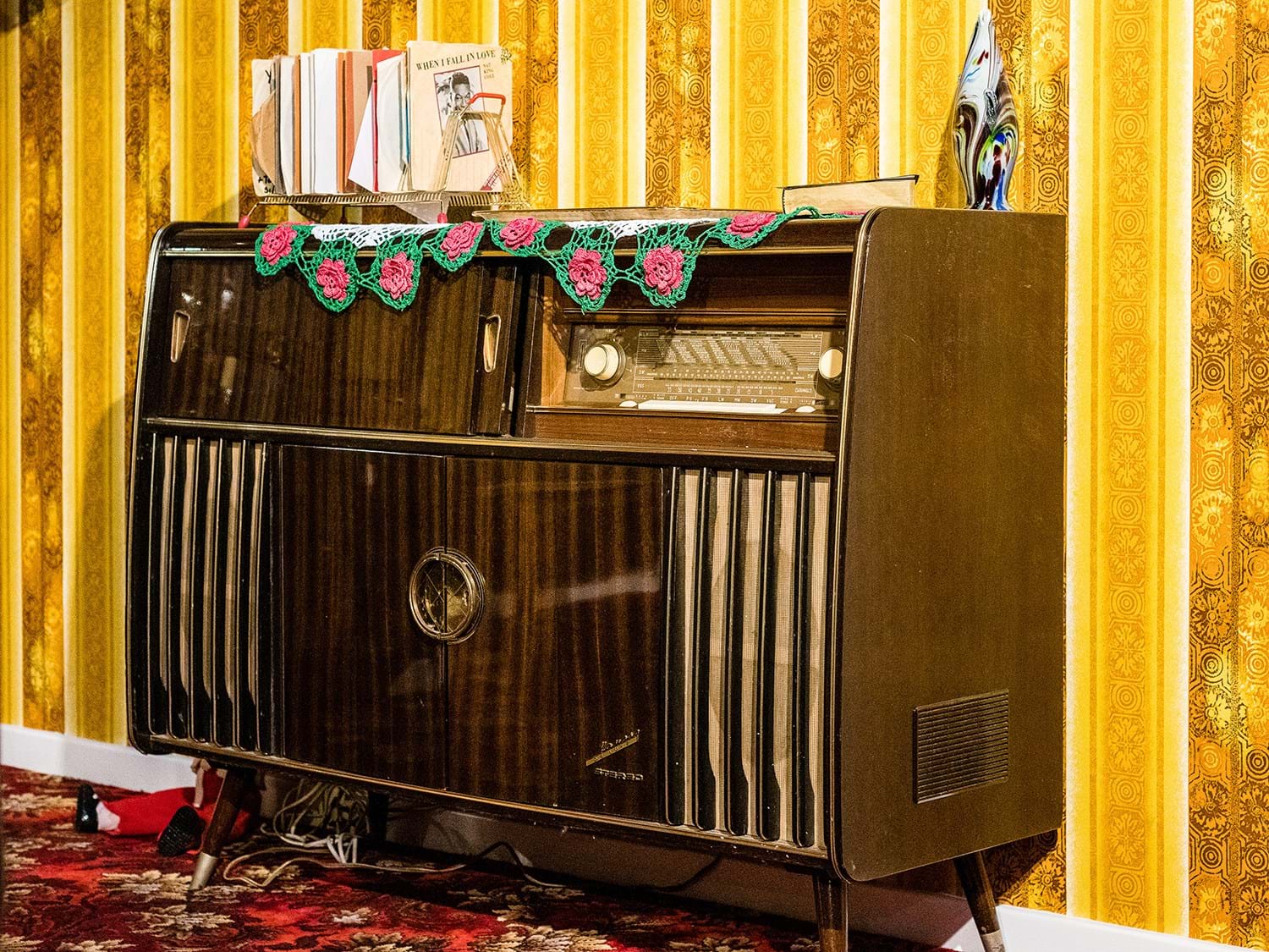 Free standing radiogram with 7 inch records on top, in a room with yellow wallpaper