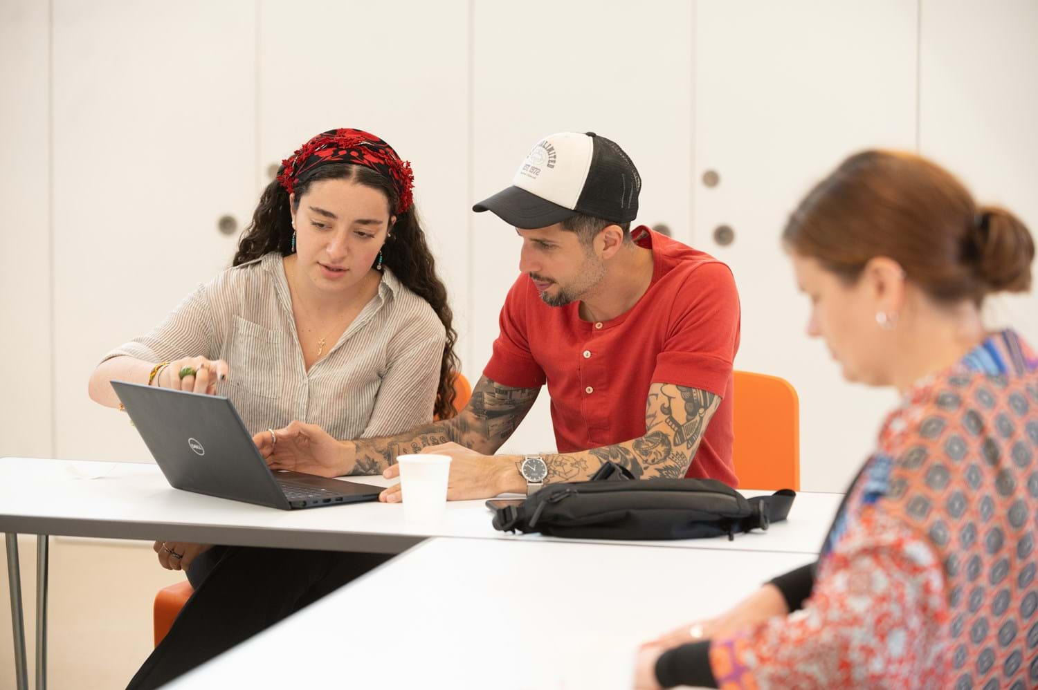 Two people look and point at a laptop while talking