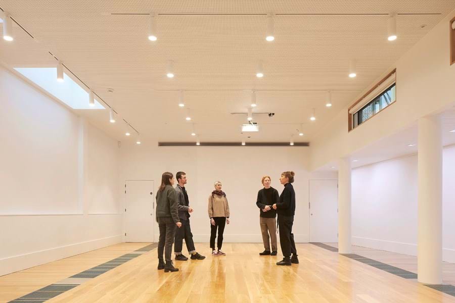 A group of people in a white room with wooden floors
