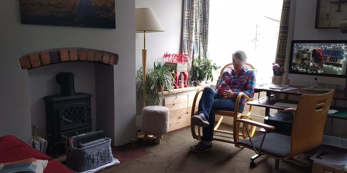 person sat in chair in living room with fireplace and plants