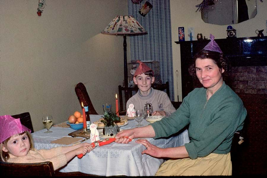 An adult and two children pulling Christmas crackers at a table