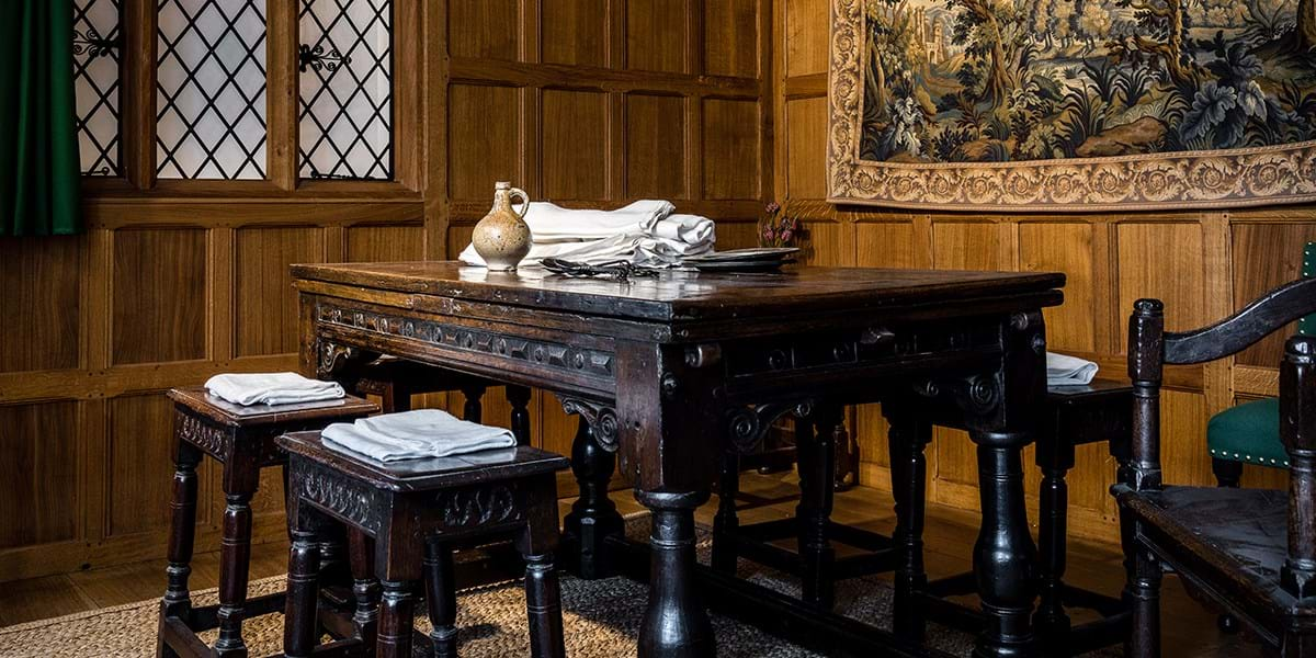 Large wooden table with stools and one large chair, in wood panelled room