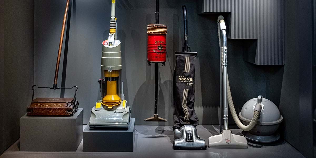 A display of five vacuum cleaners from throughout the years