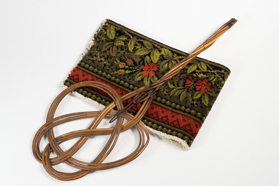 A wicker carpet beater on a fabric bag decorated with a floral pattern.