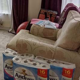 Packs of loo roll stacked against a sofa
