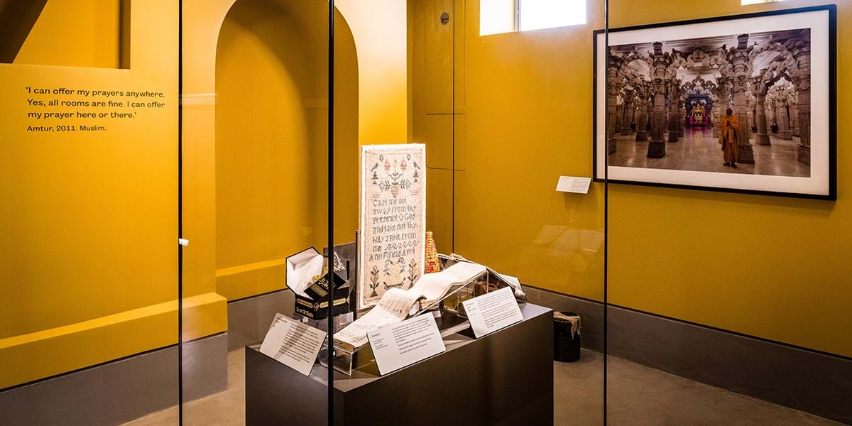 A glass cabinet filled with religious objects in room painted yellow