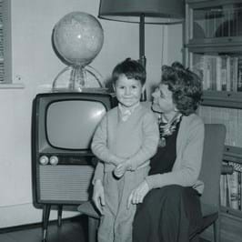 Black and white image of two people sitting together in front of a television set 