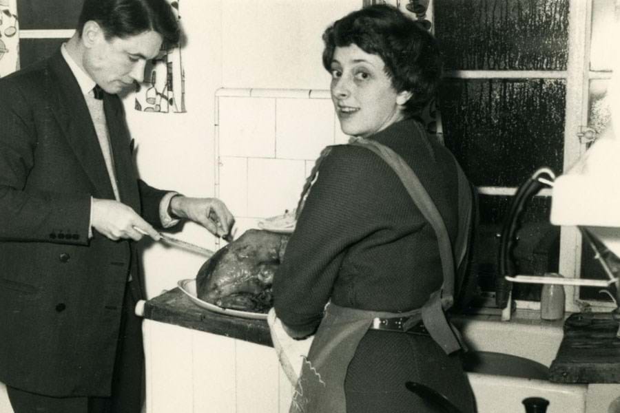 Black and white photo of two people carving a turkey
