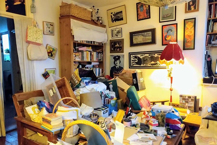 A room cluttered with various objects including books and sewing materials
