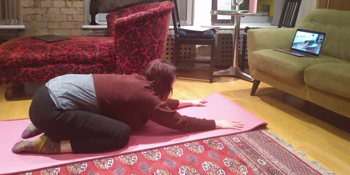 A person doing yoga on a pink mat on a rug