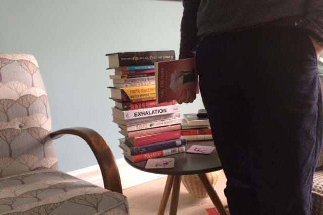 Pile of books on a table next to an armchair