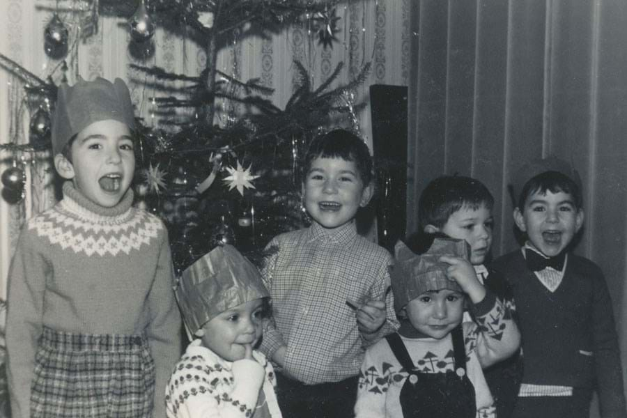 A group of children standing in front of a Christmas tree