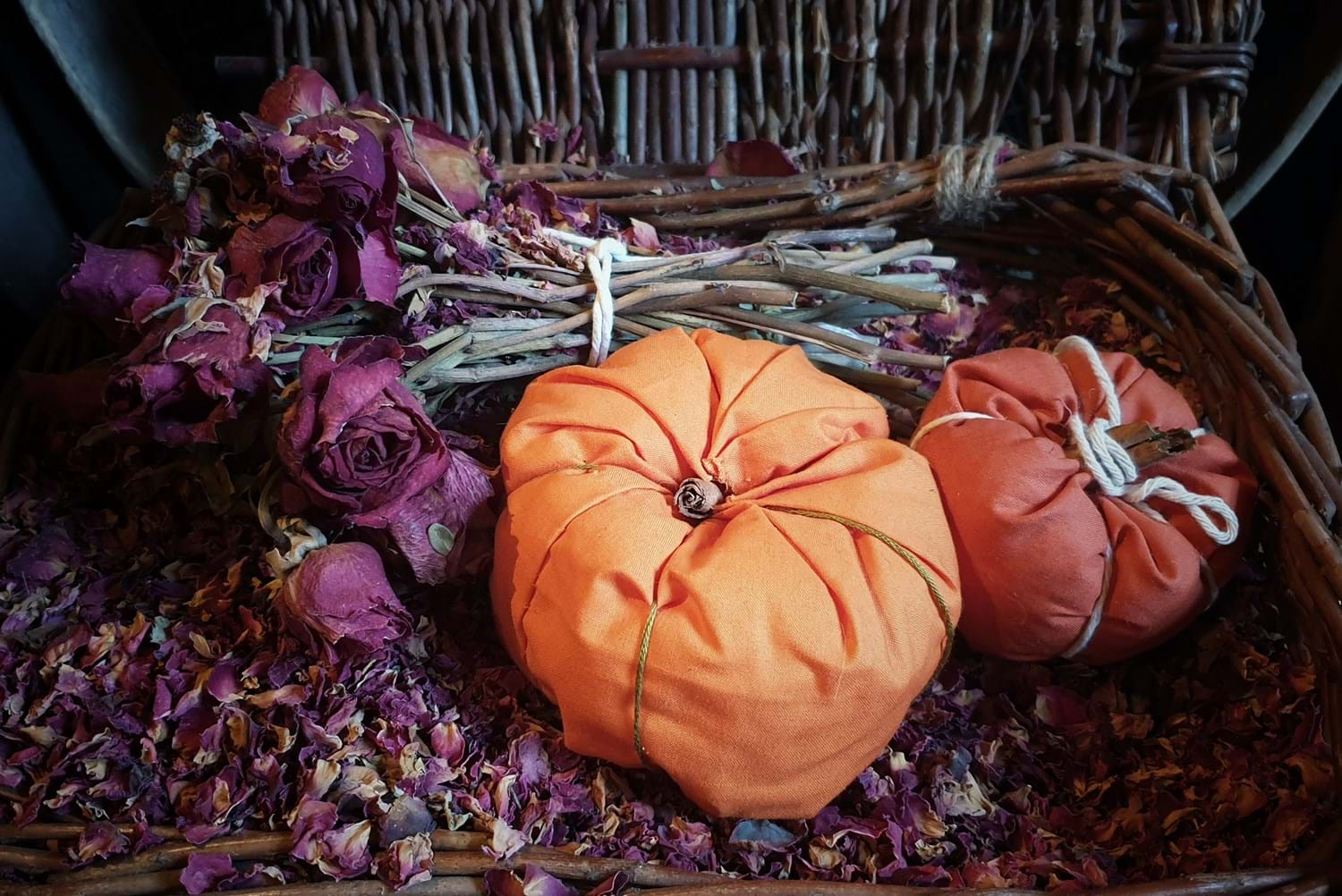 Two pomanders sit in a basket of dead rose petals