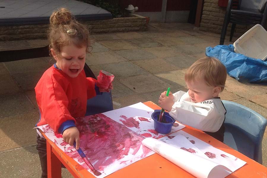Children painting on paper on a small table 