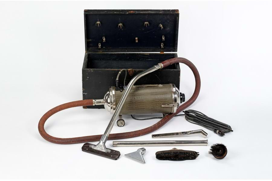 Vacuum cleaner from the 1930s in silver, with brown nozzle. It comes in a large black case.