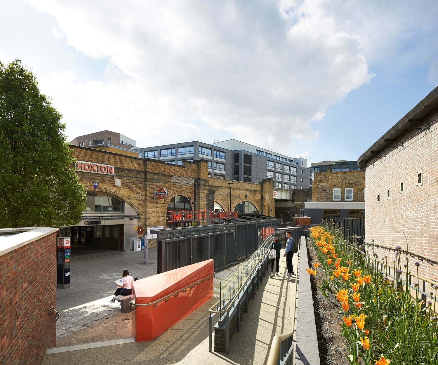 Entrance to Museum of the Home with Hoxton overground station visible in the background and a wheelchair accessible pathway lined with flowers to enter the museum