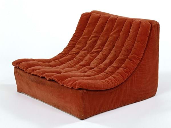 Low soft chair covered with orange fabric 