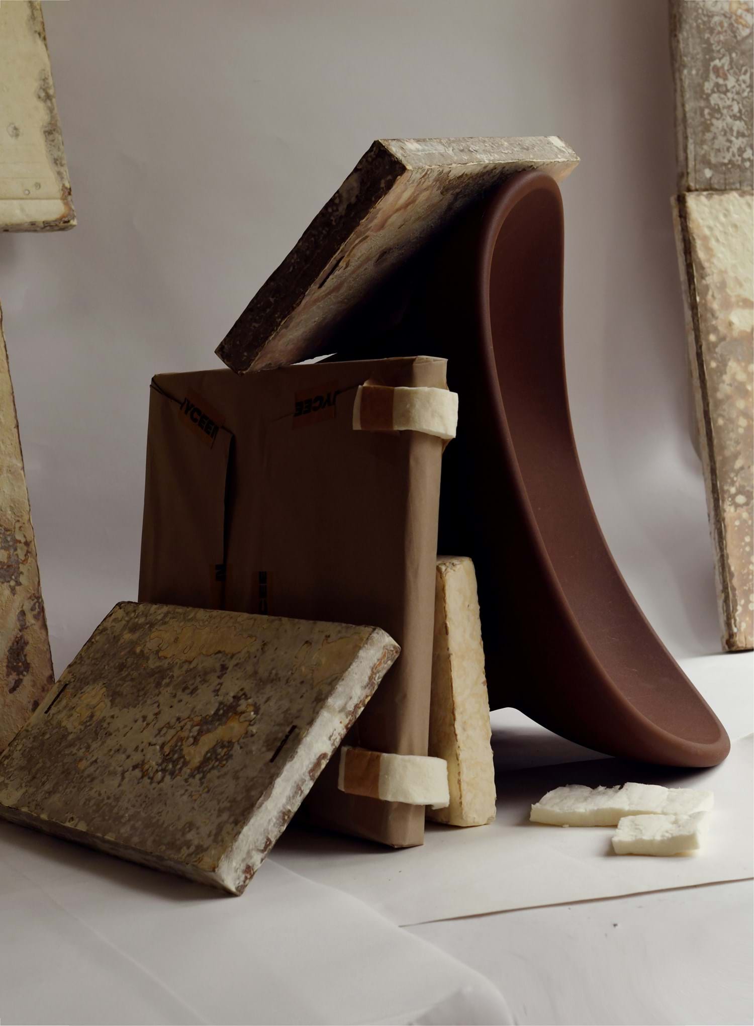 Objects from the 2049 room at the museum including a modern brown chair and panels of mycelium insulation panels leaning against each other.