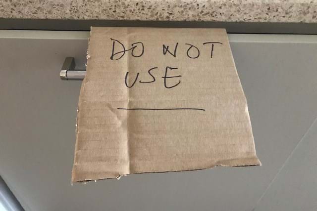Cardboard sign that says Do Not Use pinned to a dishwasher