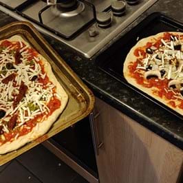 Two uncooked pizzas on a kitchen counter
