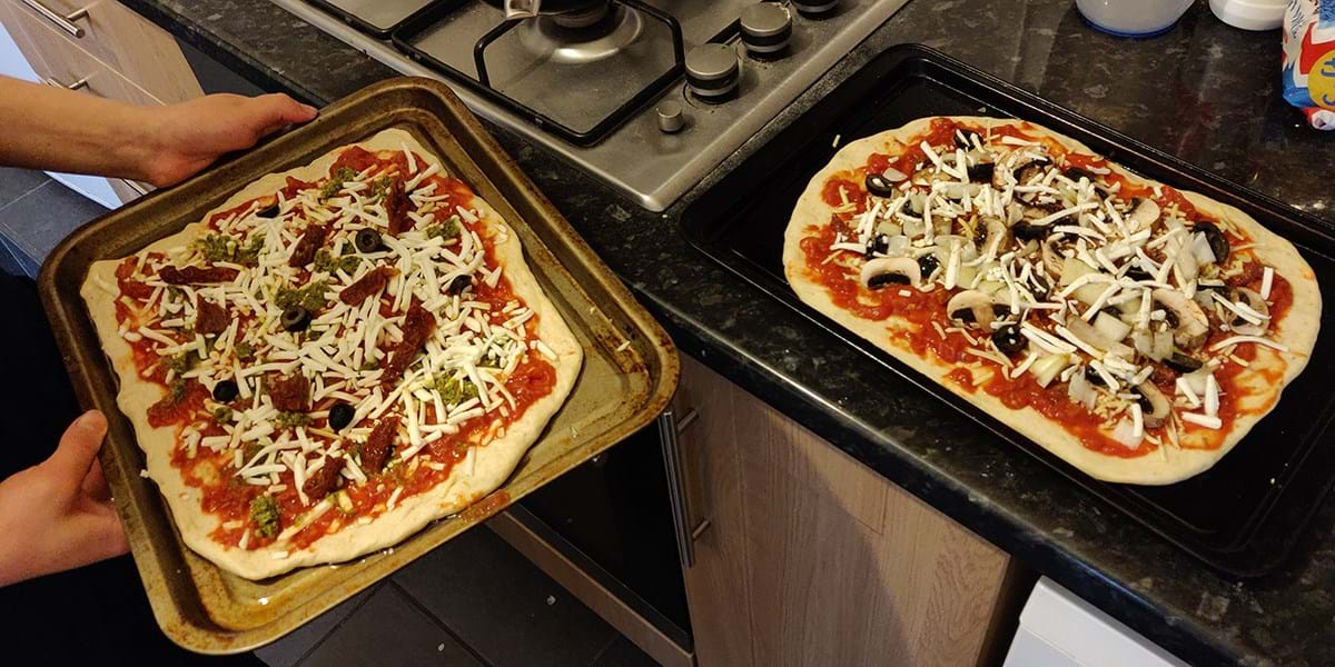 Two uncooked pizzas on a kitchen counter