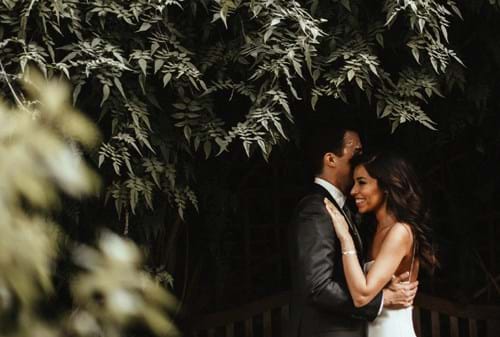 Two people embracing in front of a hedge