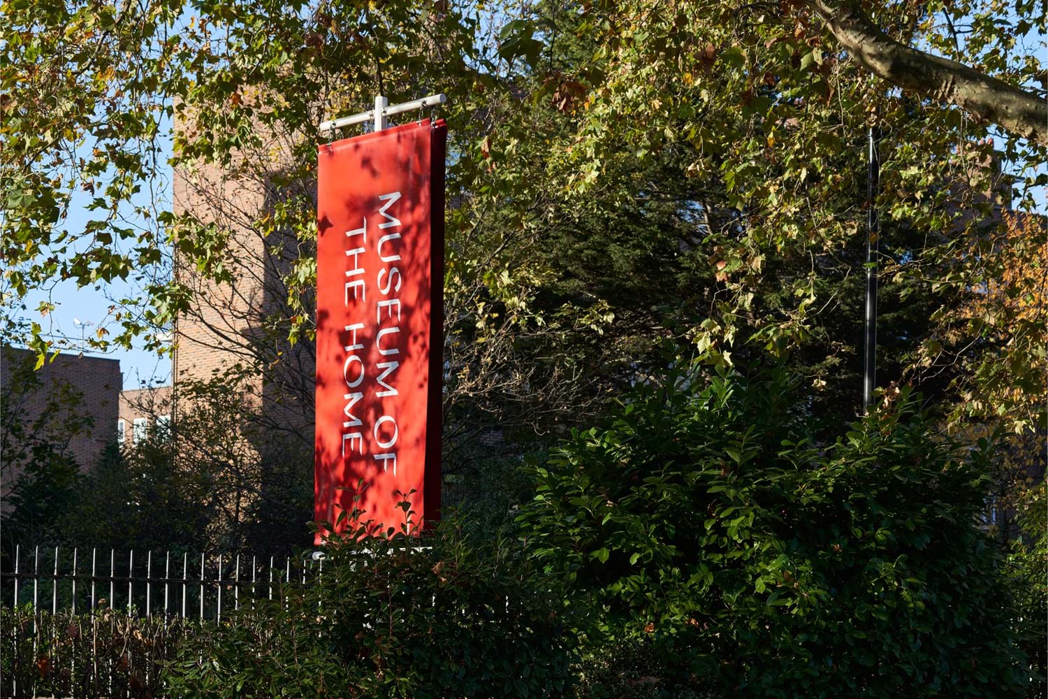 Vertical flag of Museum of the Home with it's logo surrounded by lush green trees