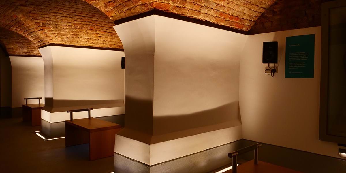 A room with white walls and vaulted brick ceilings