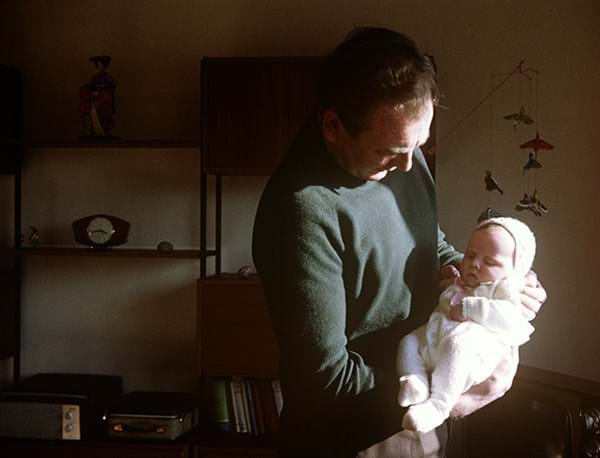 Person holding a baby with clock in the background