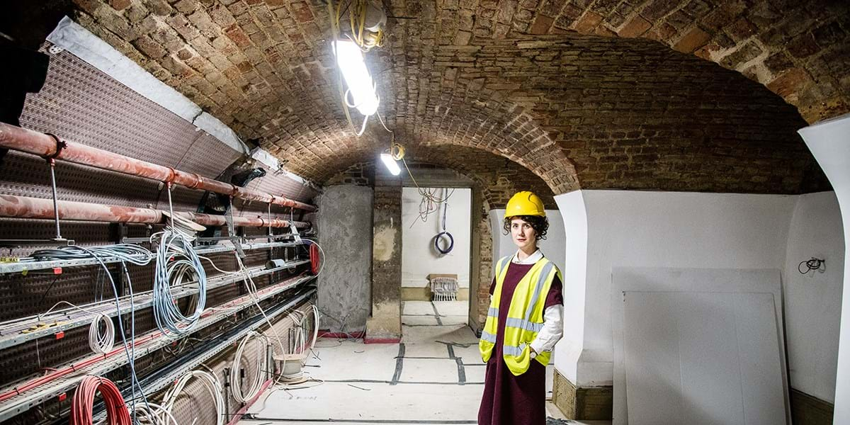 Director Sonia Solicari wearing a hard hat in the Undercroft with newly plastered walls