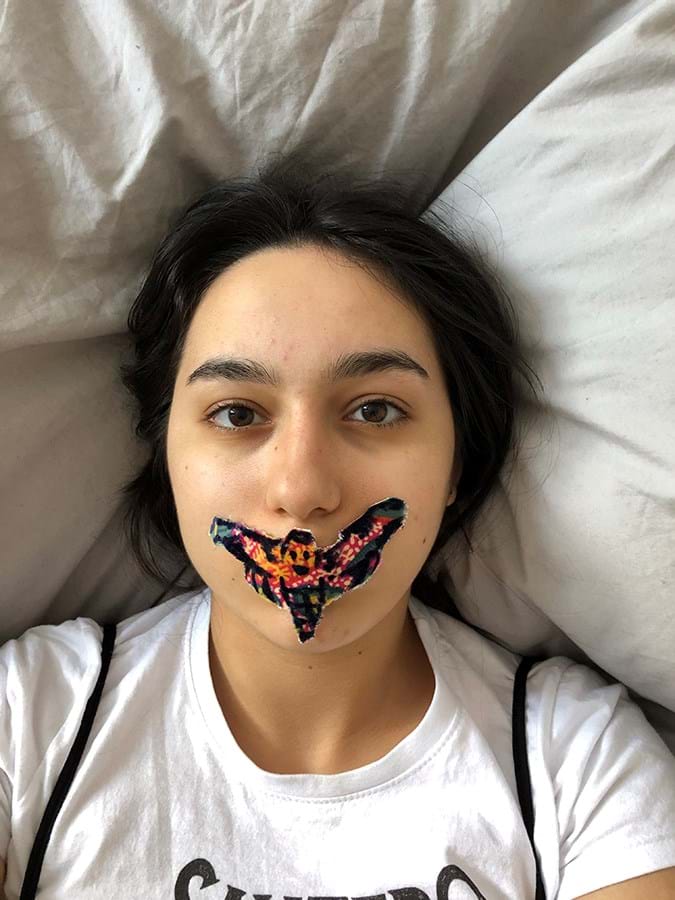 Close up portrait of a person with a butterfly covering their mouth