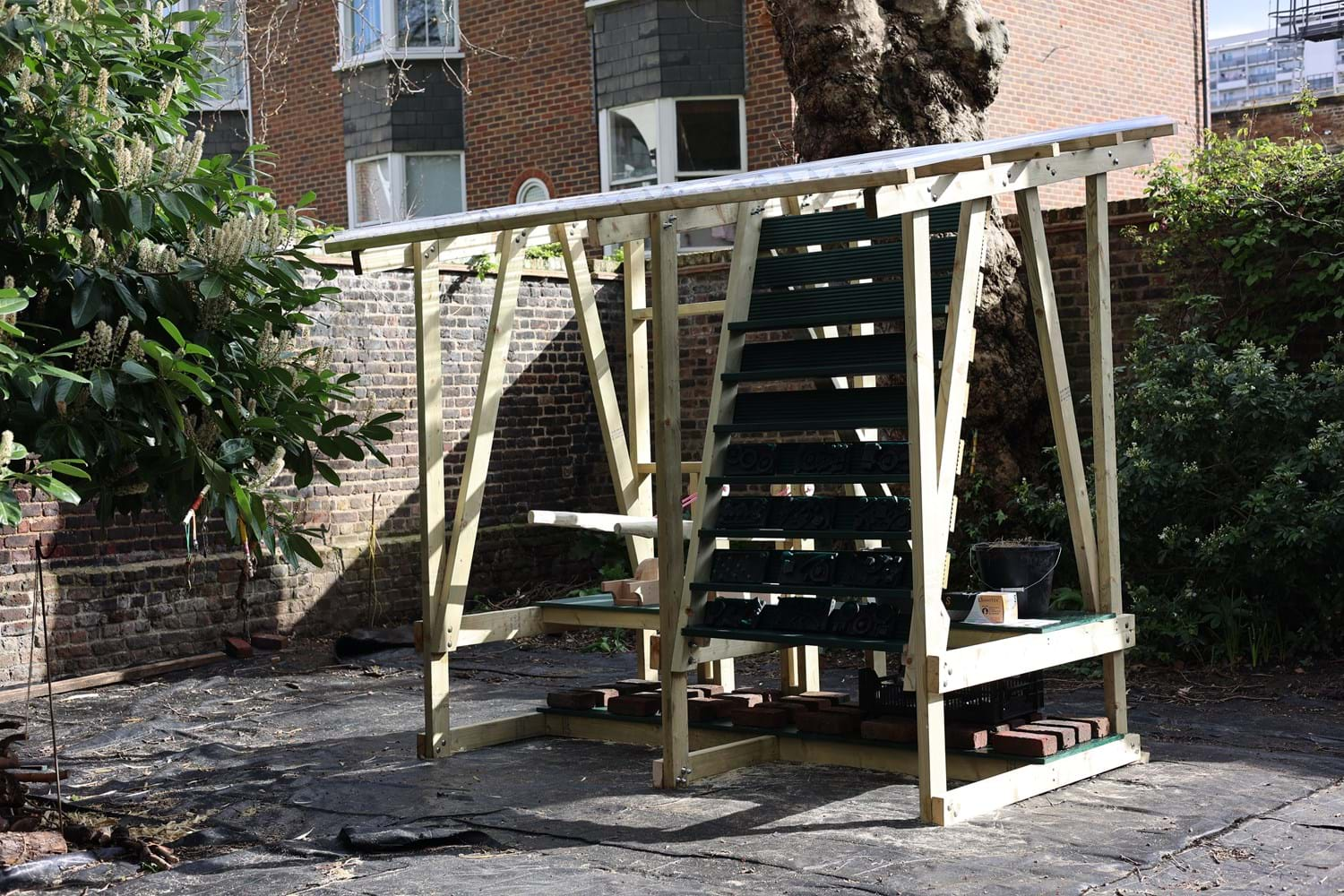 A wooden structure in a garden with handmade bricks on display