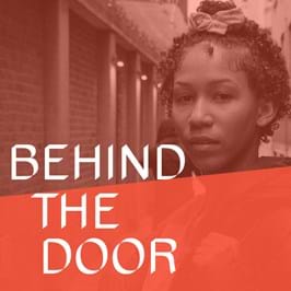 A person looking towards the camera, with text overlaid that reads 'behind the door'
