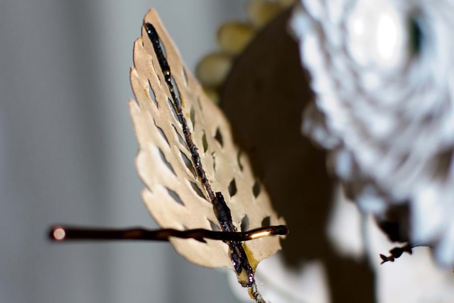 A close up of a hair clip holding a decorative leaf