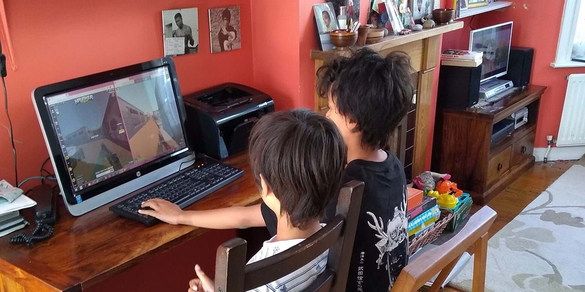 Two children at a desk using a desktop computer 