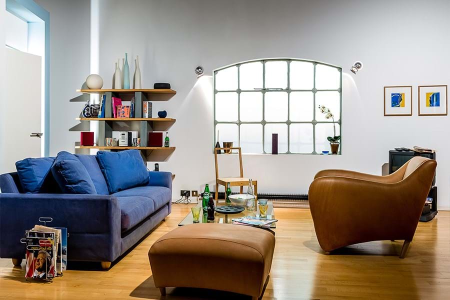 Open plan living room and kitchen with blue sofa, brown leather armchair and black television set 