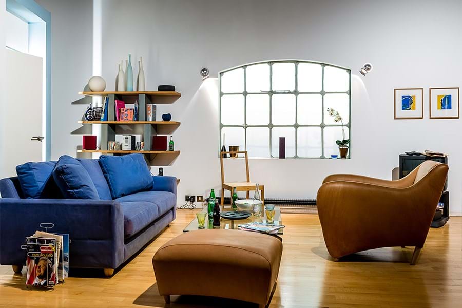Open plan living room and kitchen with blue sofa, brown leather armchair and black television set