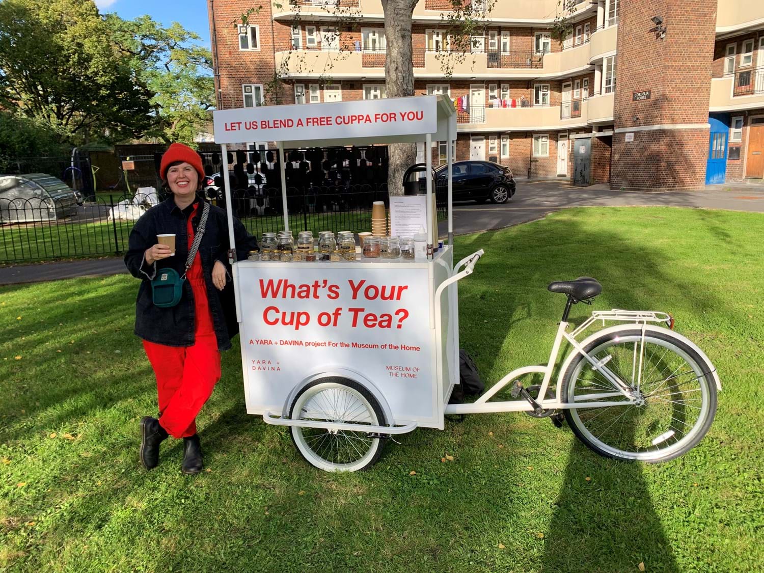 A white and red wagon with the words "What's your cup of tea?" displayed, with a person in red overalls holding a cup of tea