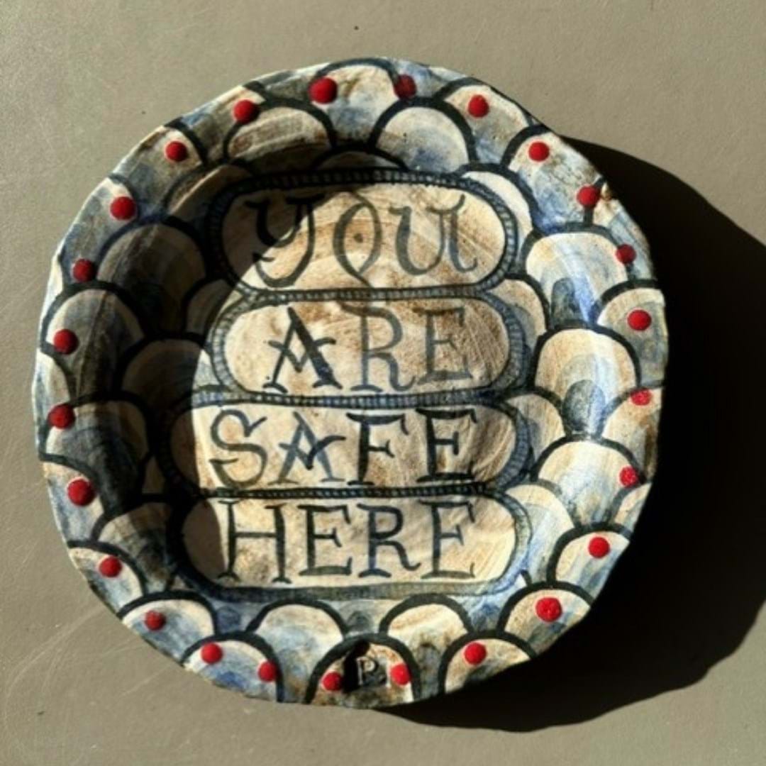 A handmade and hand painted ceramic plate with the words 'you are safe here' 