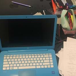 Open laptop with a glass of liquid on the left and papers on the right