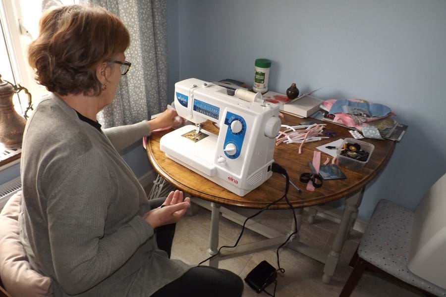 A person making face masks at a sewing machine