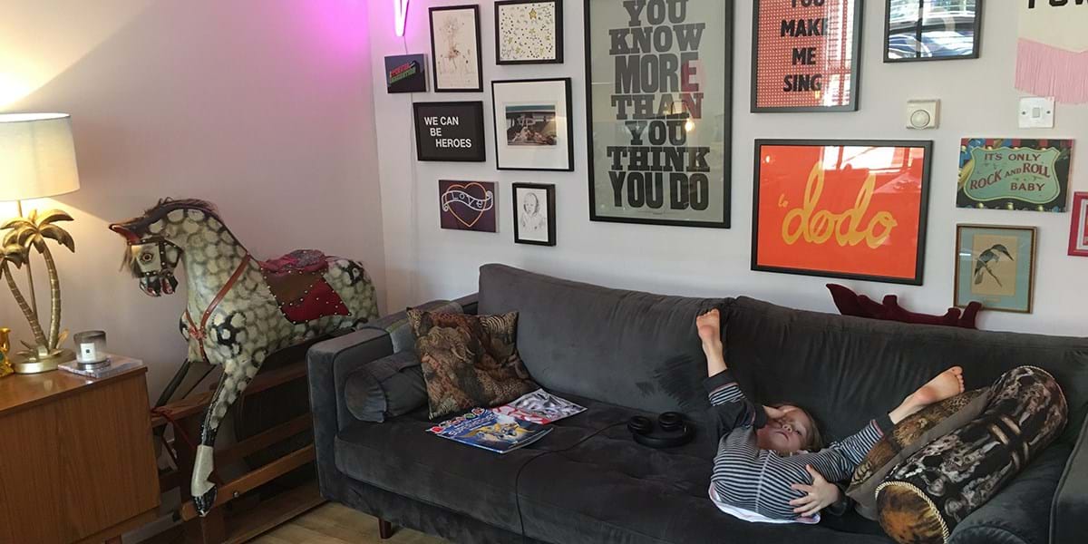 Child lying on sofa with various prints hung on the wall behind